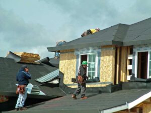 A homeowner examining shingles and gutters for storm damage in a residential neighborhood.