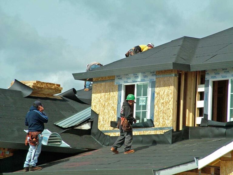 A homeowner examining shingles and gutters for storm damage in a residential neighborhood.